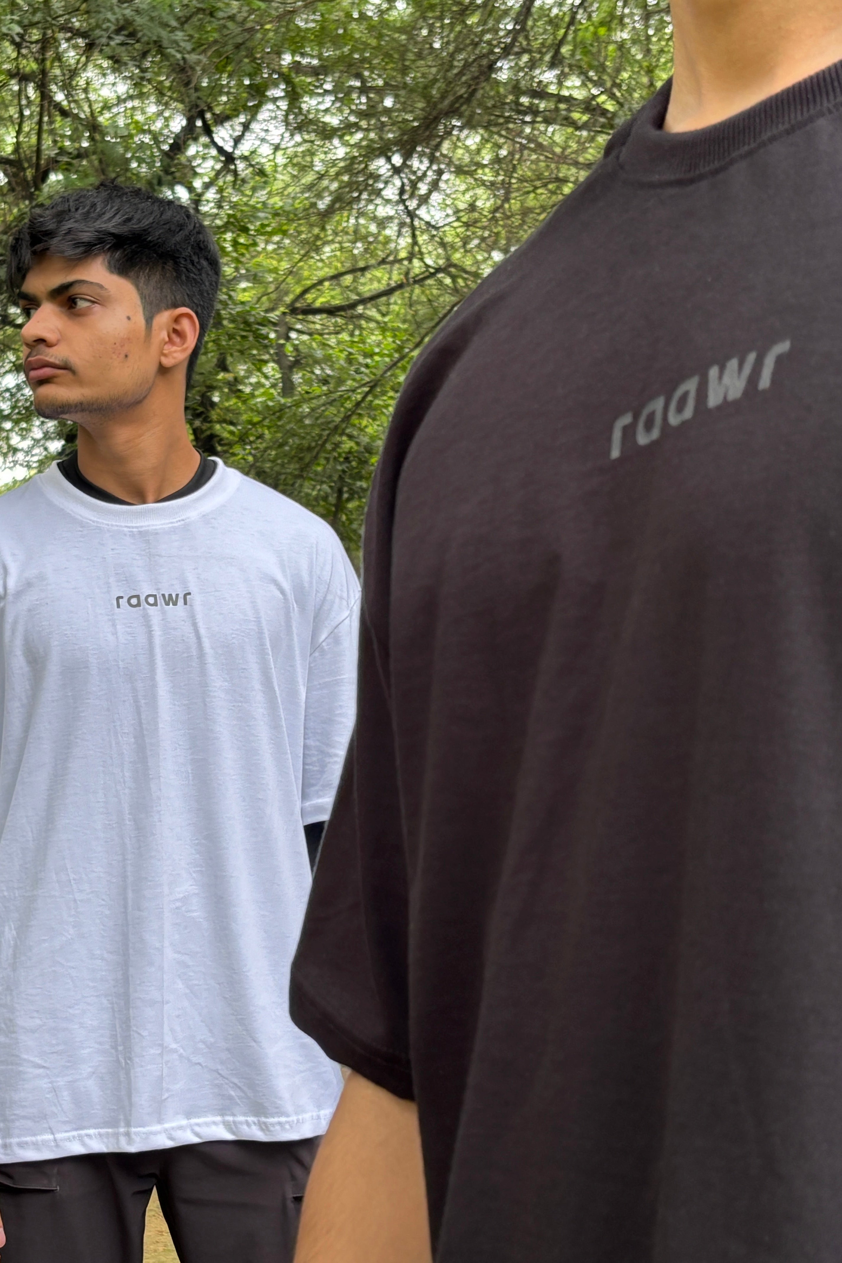 Two people wearing 'raawr' branded t-shirts in a forest setting